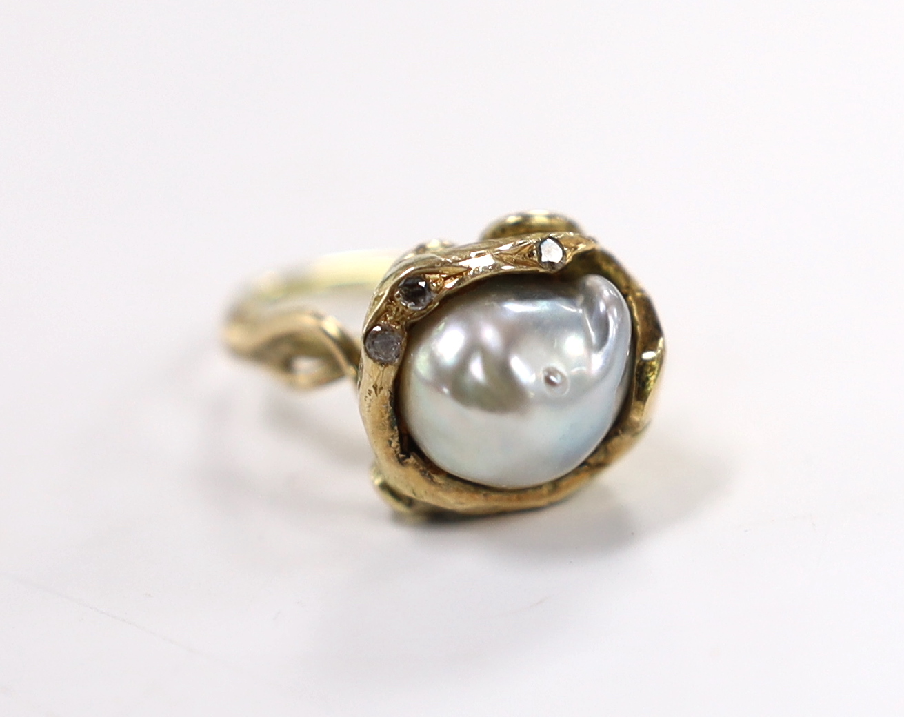 A yellow metal and baroque pearl set ring, with three stone diamond chip set setting, of foliate form, size K, gross weight 6.7 grams.